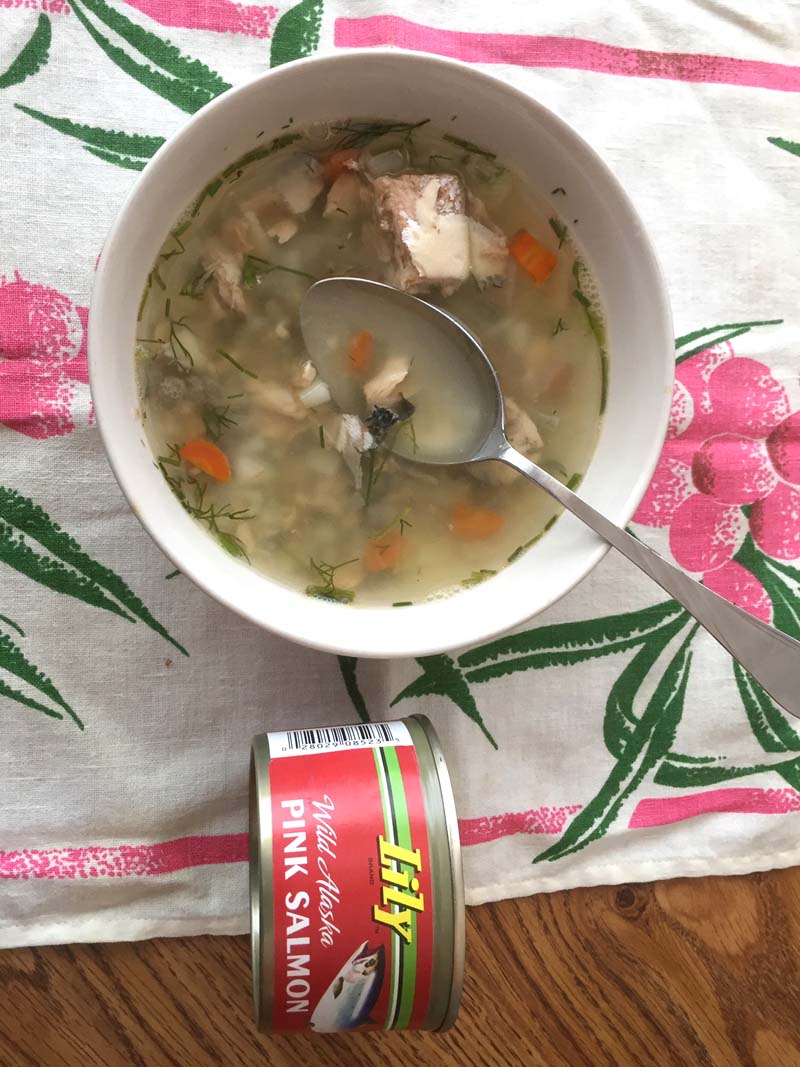 The soup in a white bowl next to the canned salmon