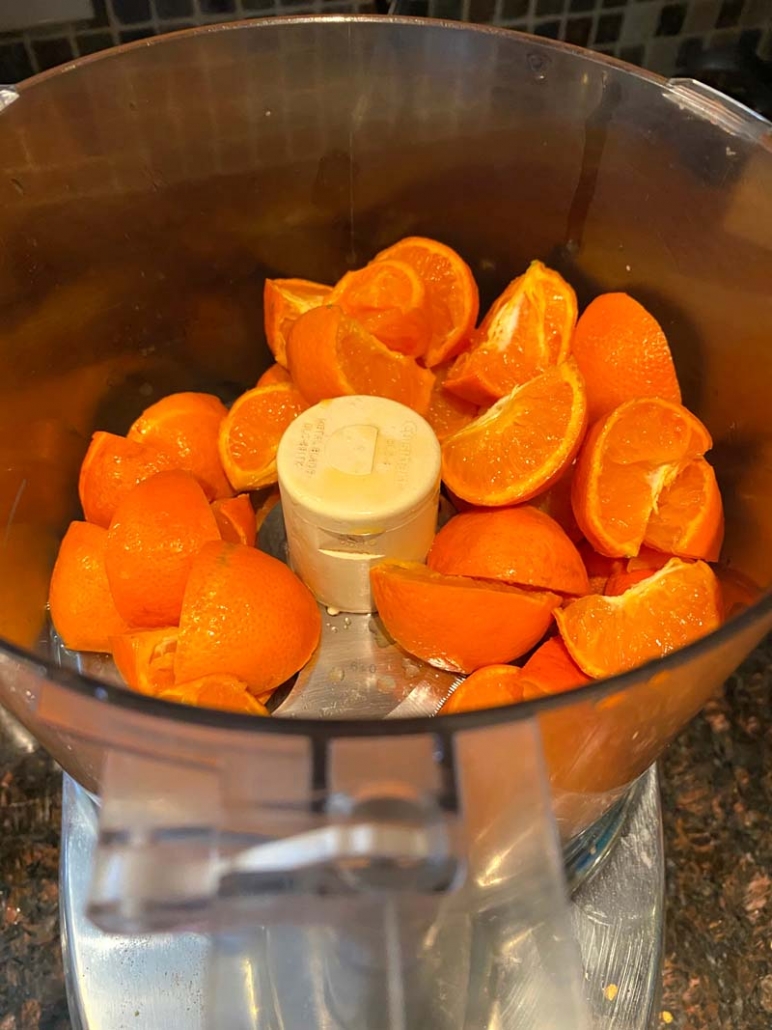 adding oranges to food processor 