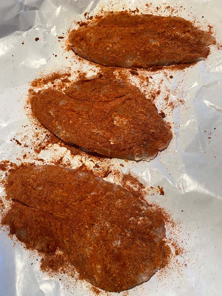 adding blackened seasoning to tilapia