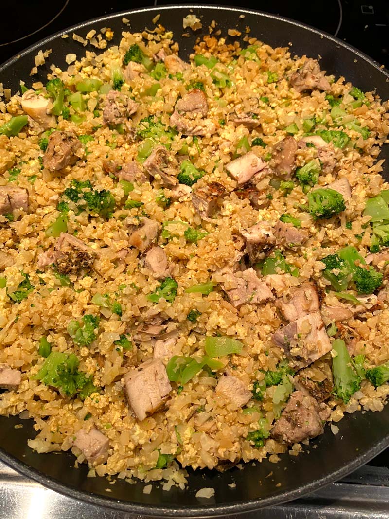 pan full of cauliflower fried rice with chicken and broccoli