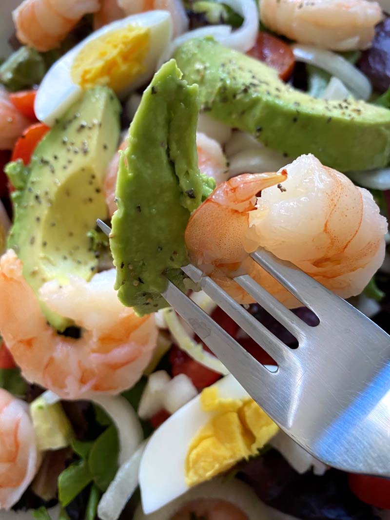 A fork with avocado and shrimp on it. 