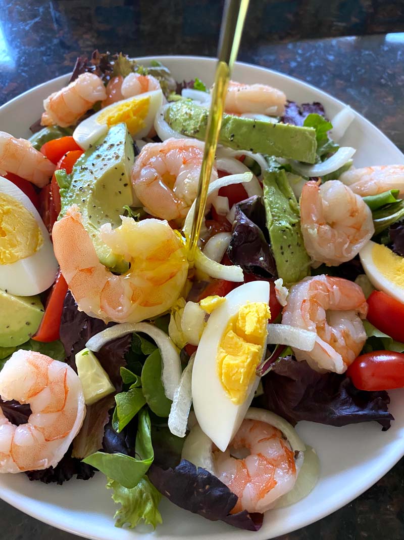 Pouring dressing on shrimp egg avocado salad 