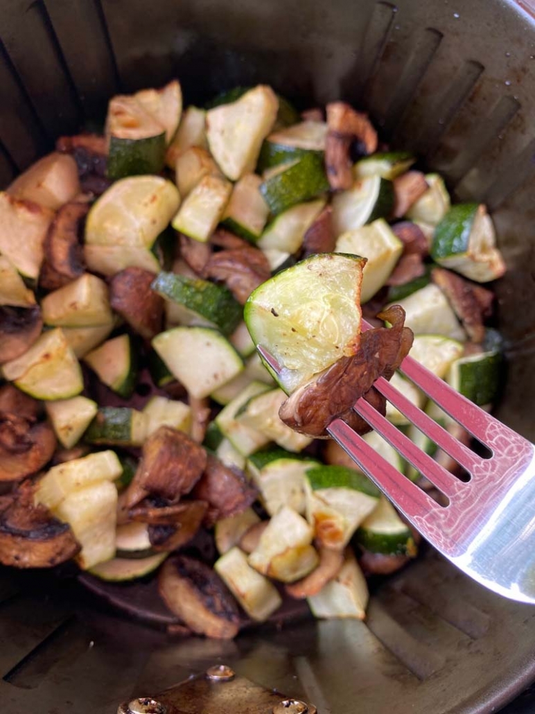 eating zucchini and mushrooms with a fork