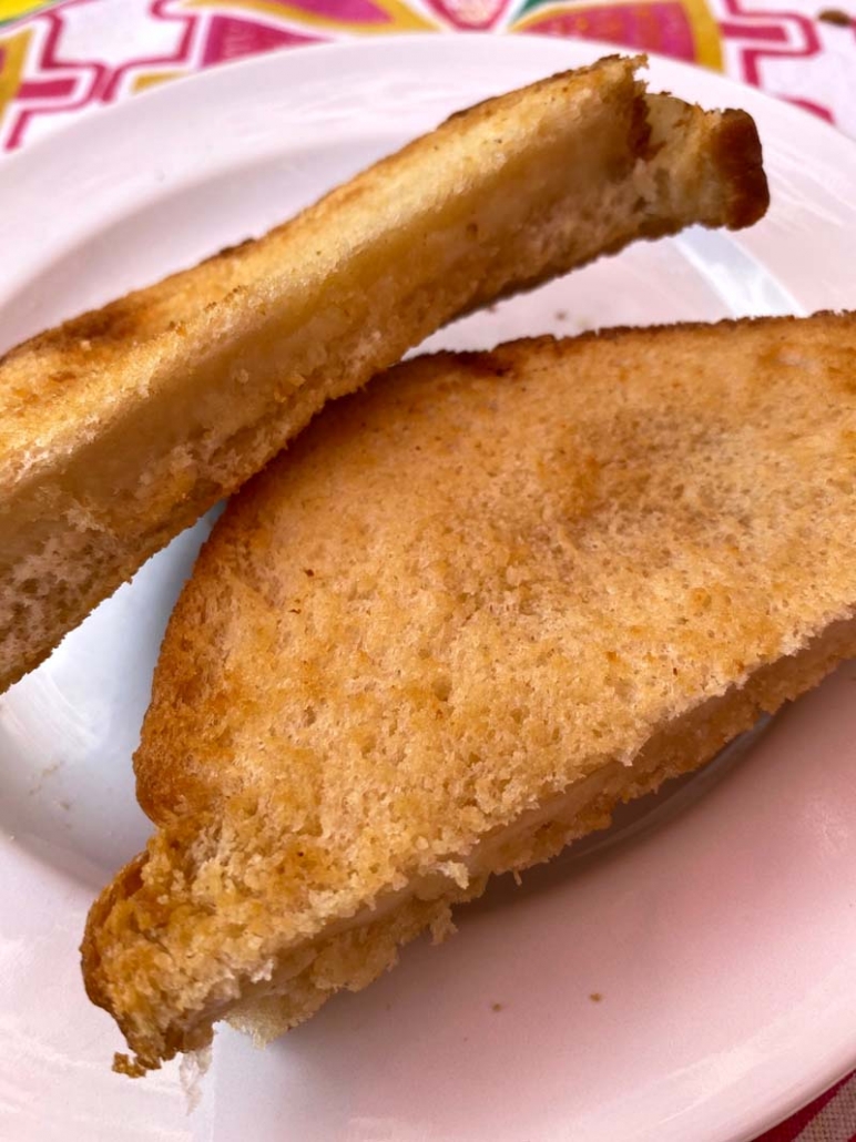 serving halved grilled cheese on a white plate 