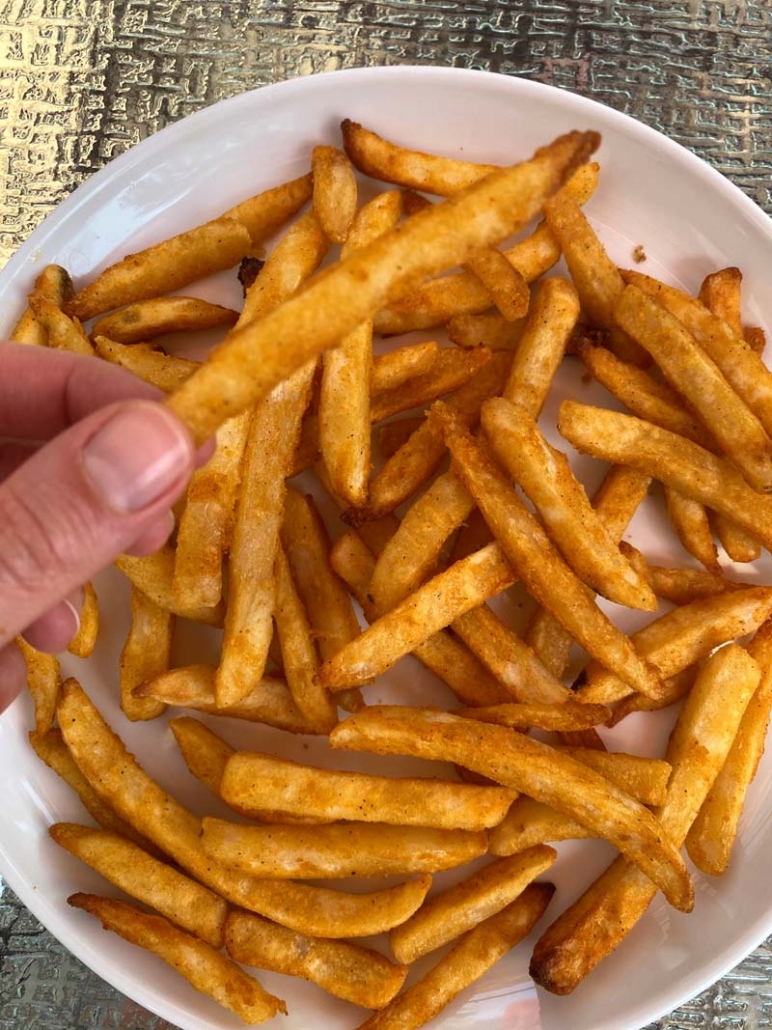 eating crispy french fries off a white plate
