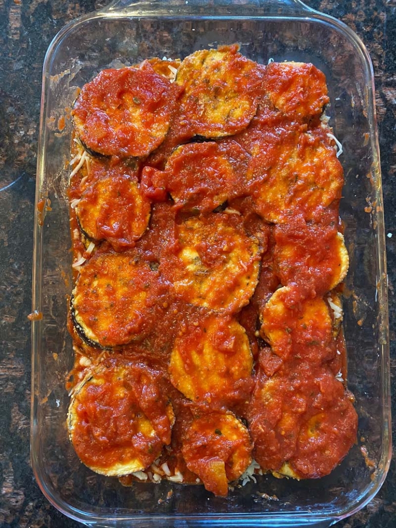 Second layer of marinara sauce on baked eggplant parmesan