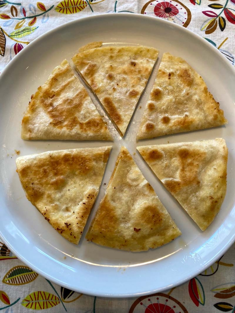 Hummus Quesadilla sliced into triangles on a white plate