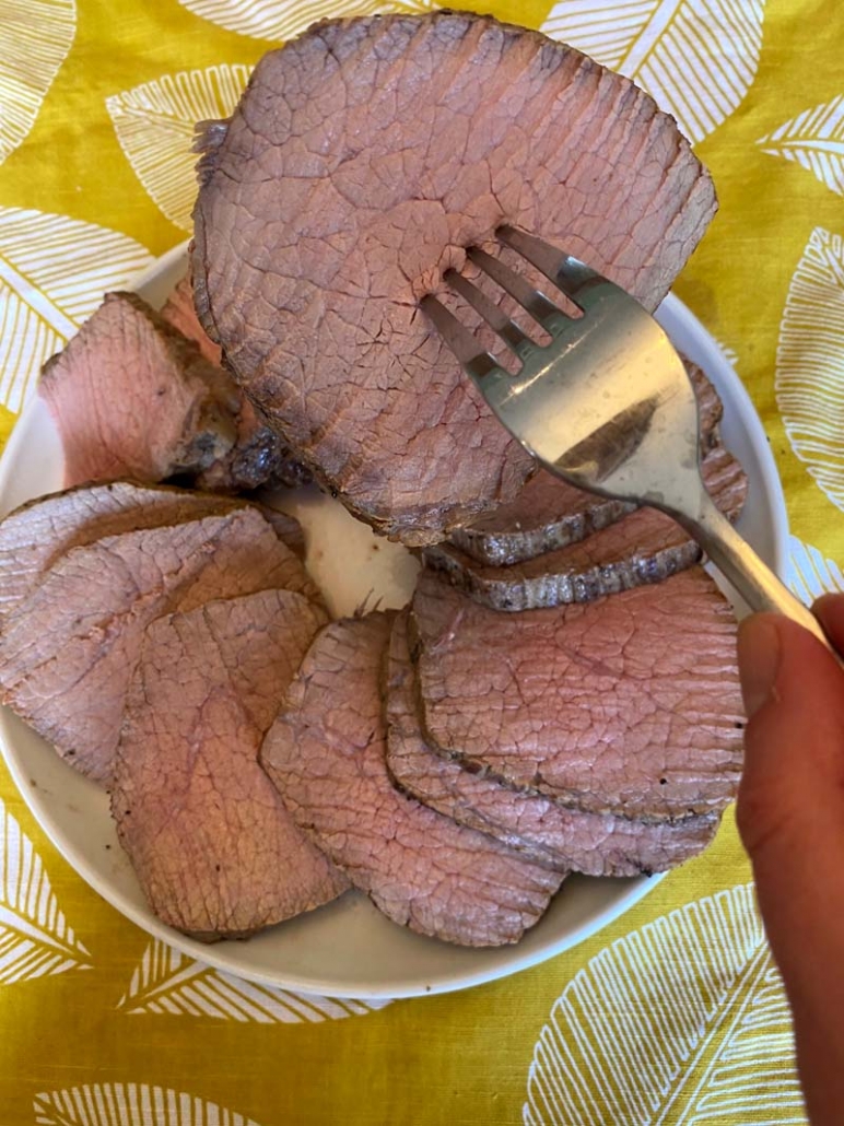 A fork with a slice of eye of round beef roast 
