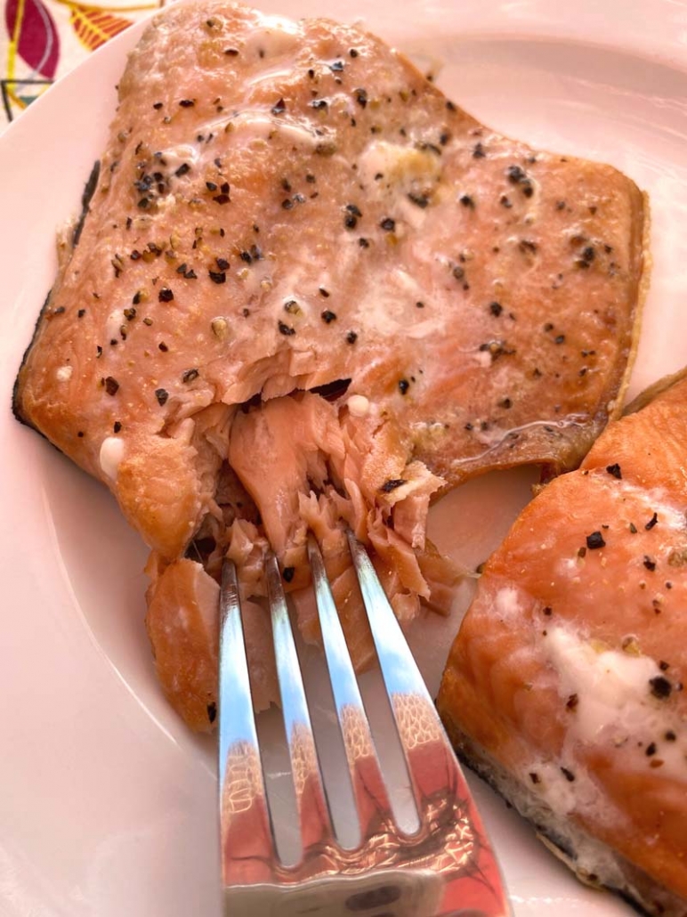 eating cooked salmon with a fork 