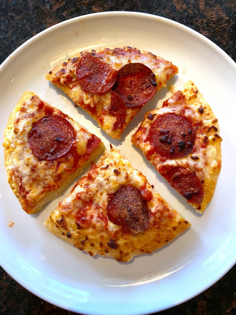 sliced personal pizza on a white plate 