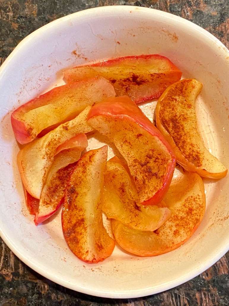 slices of red apples with cinnamon in a white bowl 
