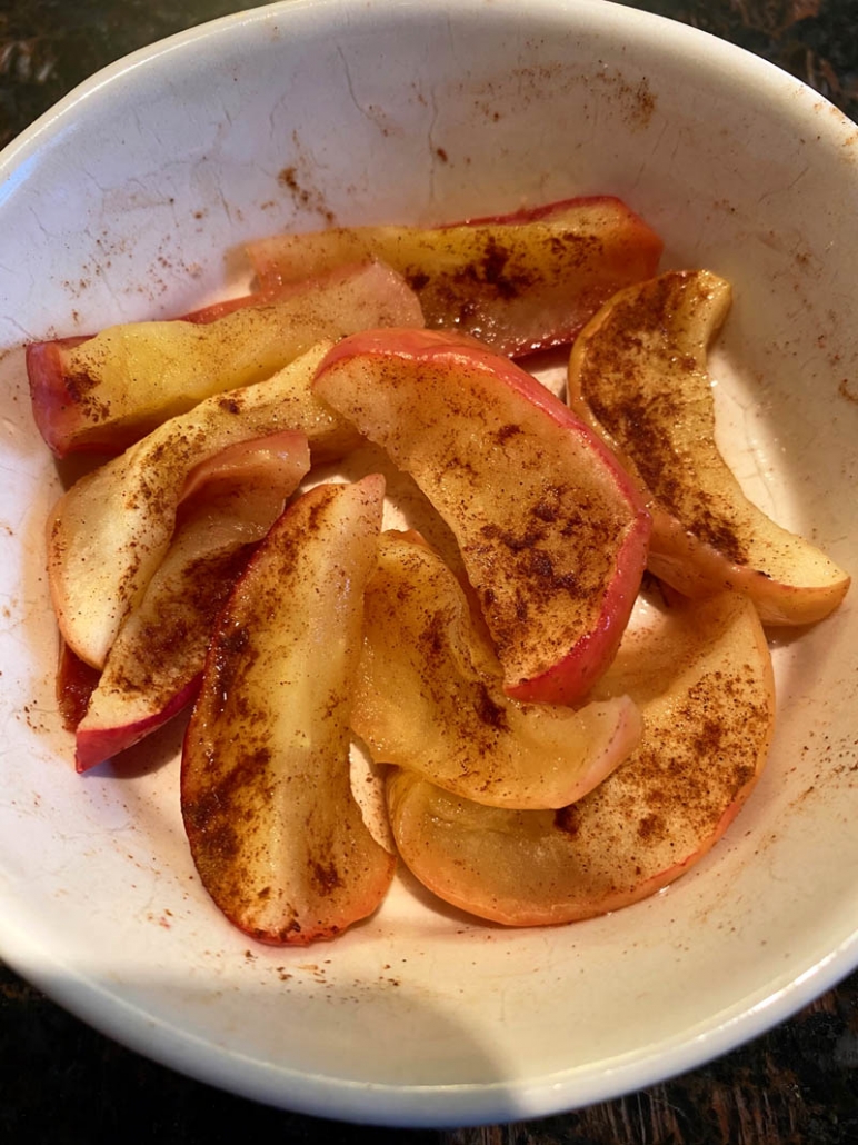 apple slices with cinnamon in a white bowl