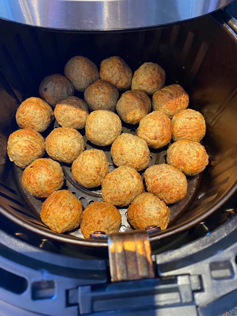 cooked meatballs in an air fryer basket 