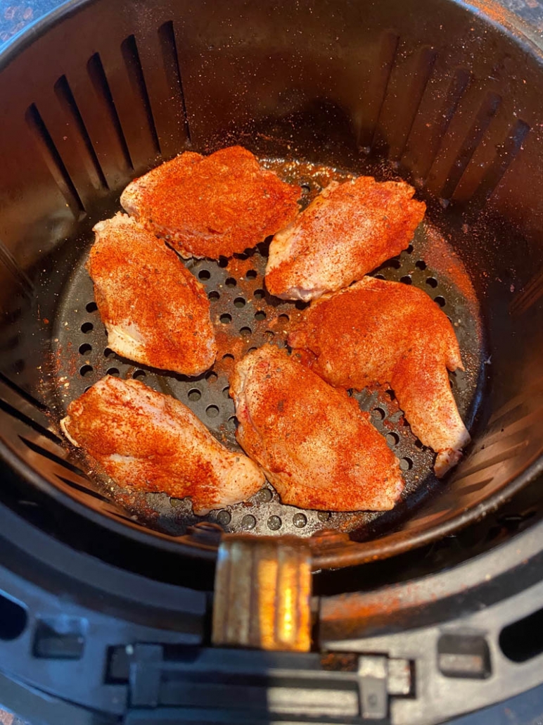 raw seasoned chicken wings in the air fryer basket 