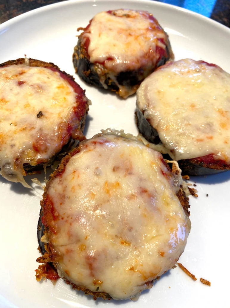 cooked eggplant parmesan on a white plate 