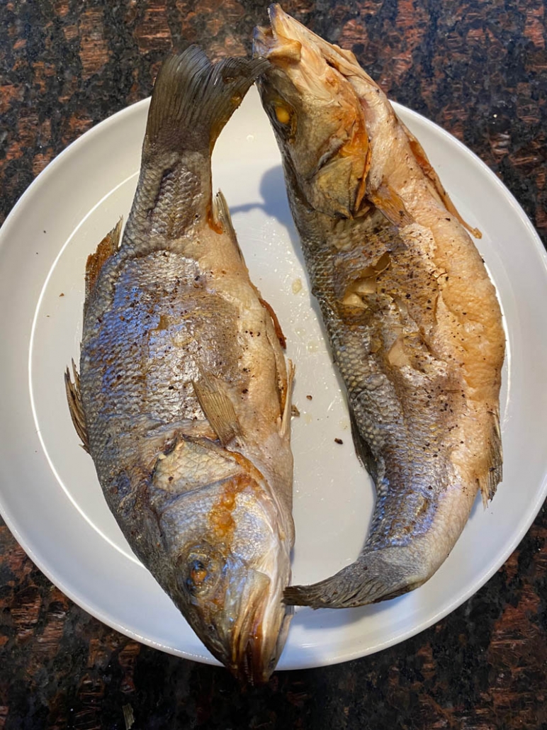 2 air fried fish on a white plate 