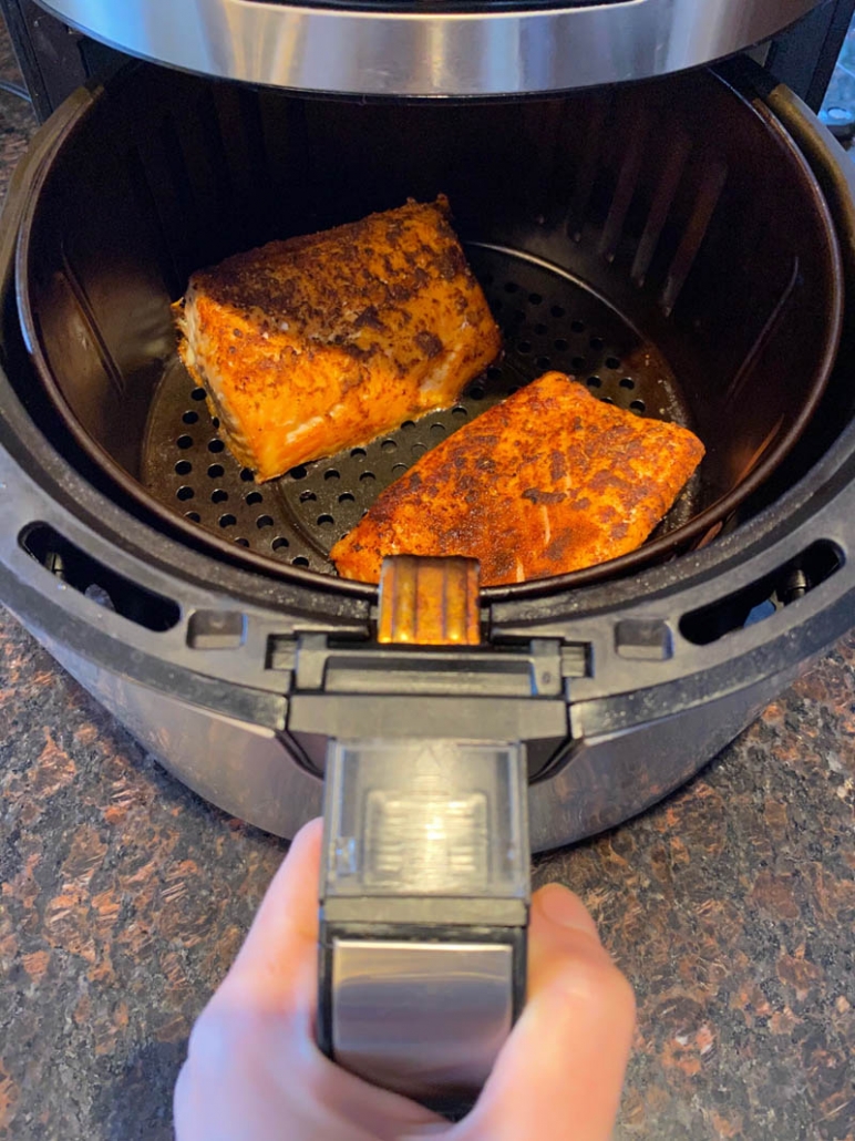 two piece of seasoned salmon in the air fryer basket 