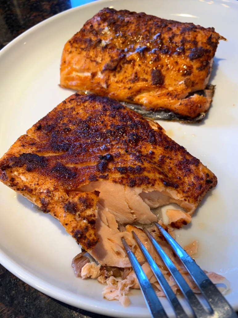 eating garlic salmon on a white plate with a fork 