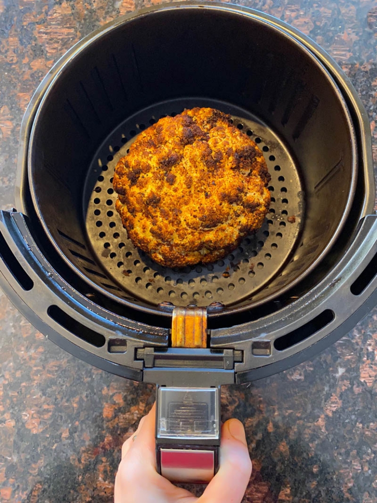 Pulling roasted cauliflower out of the air fryer 