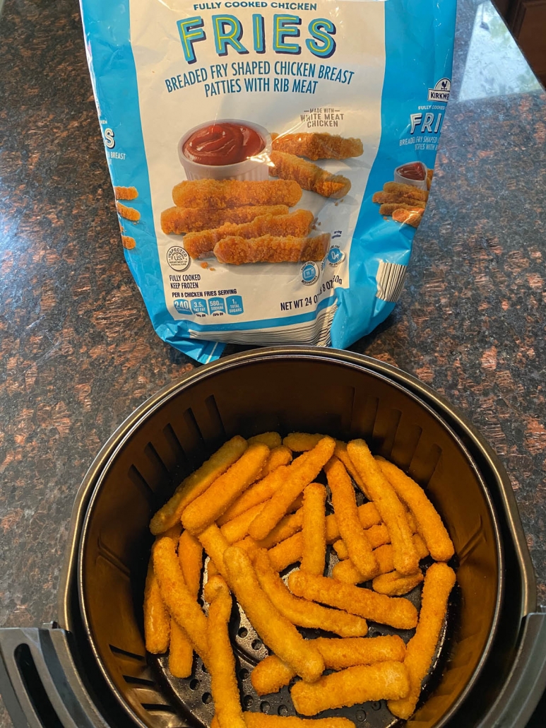 adding frozen chicken fries in an air fryer basket 