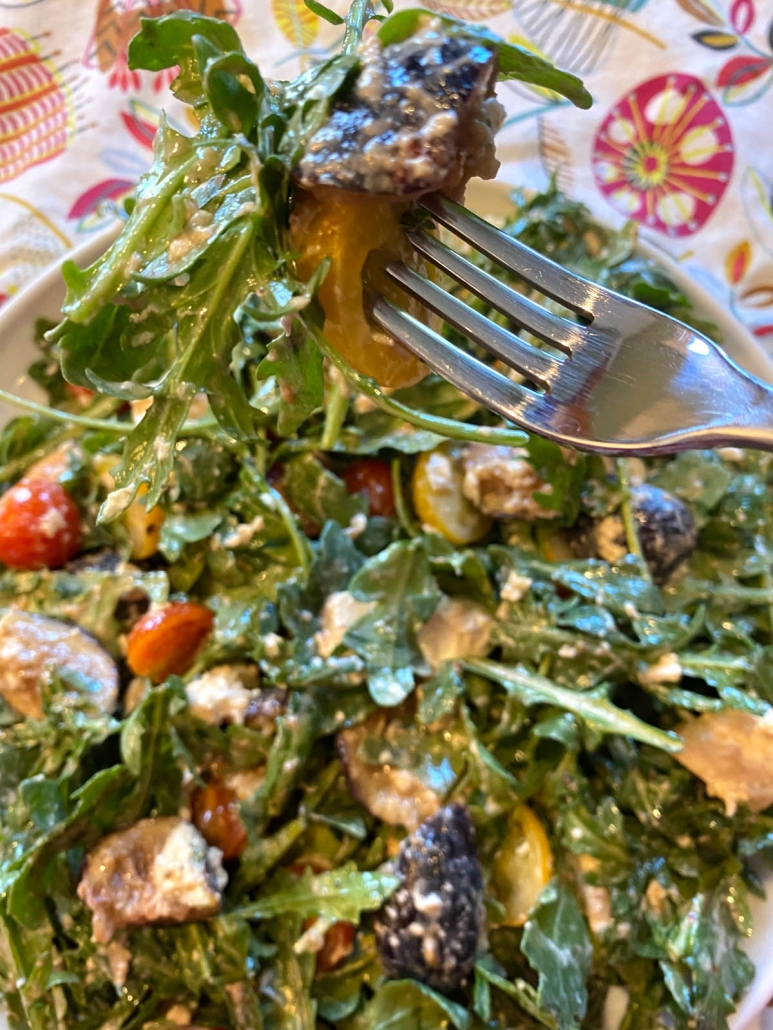 eating arugula burrata salad with a fork 