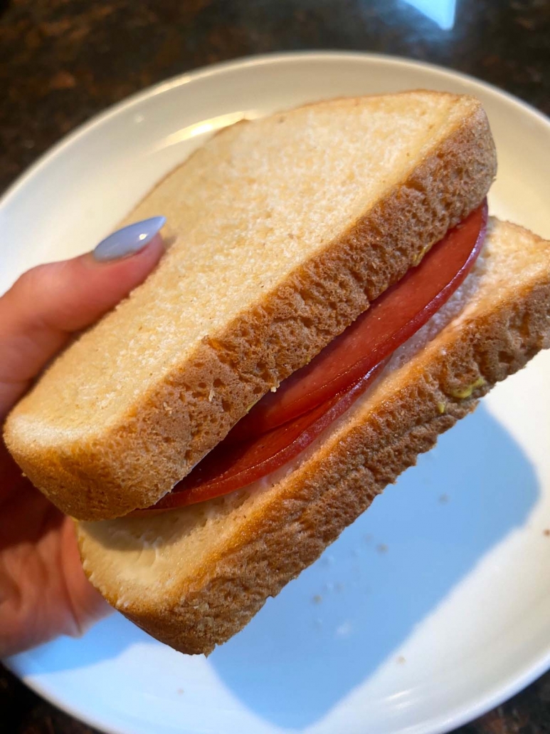 hand holding sandwich with air fried bologna slices