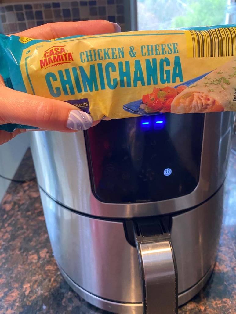 package of chimichanga held in front of air fryer