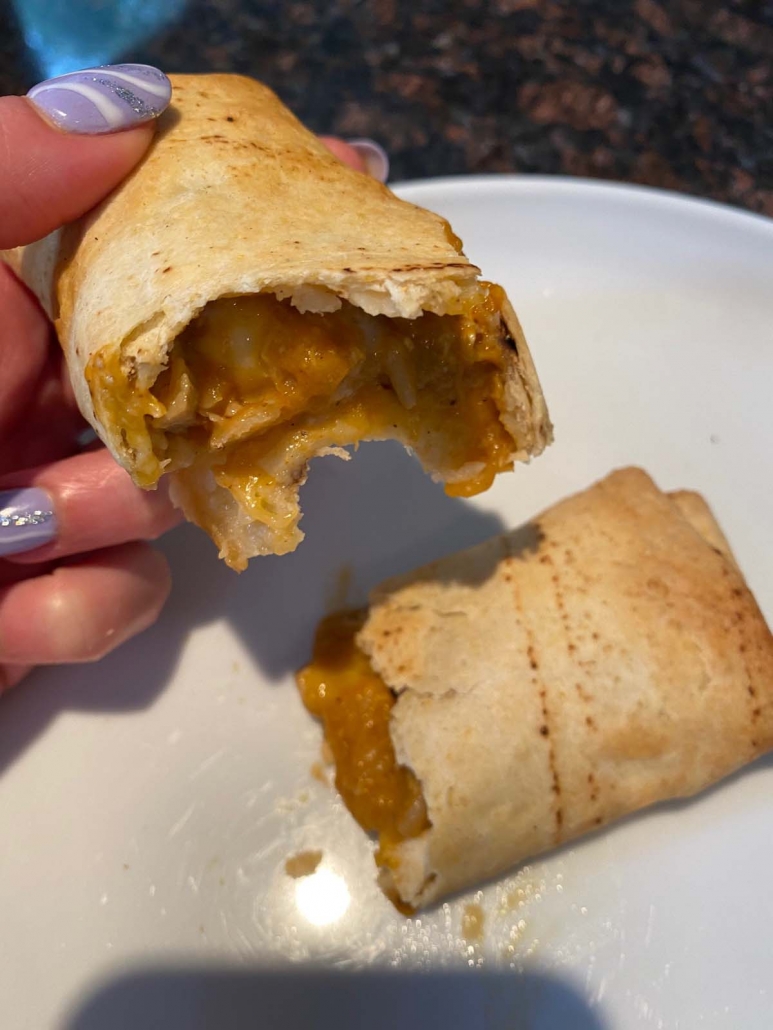 hand holding cut open chimichanga on plate