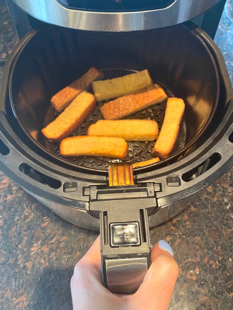 hand holding air fryer basket with french toast sticks