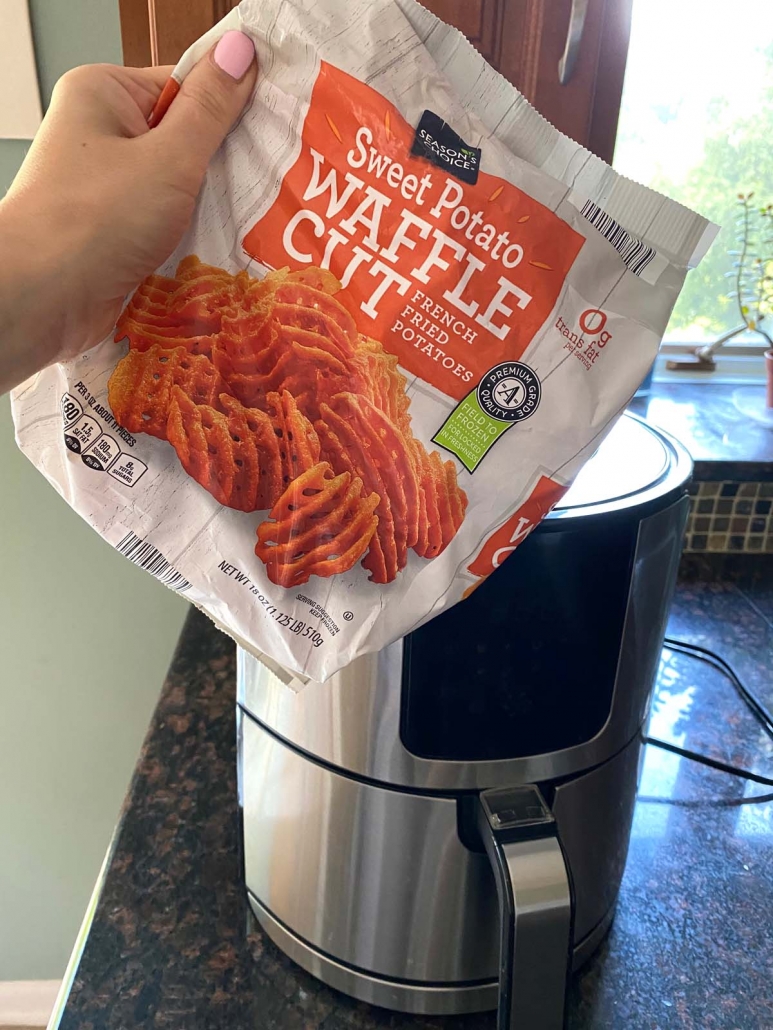 bag of frozen sweet potato waffle fries held in front of air fryer