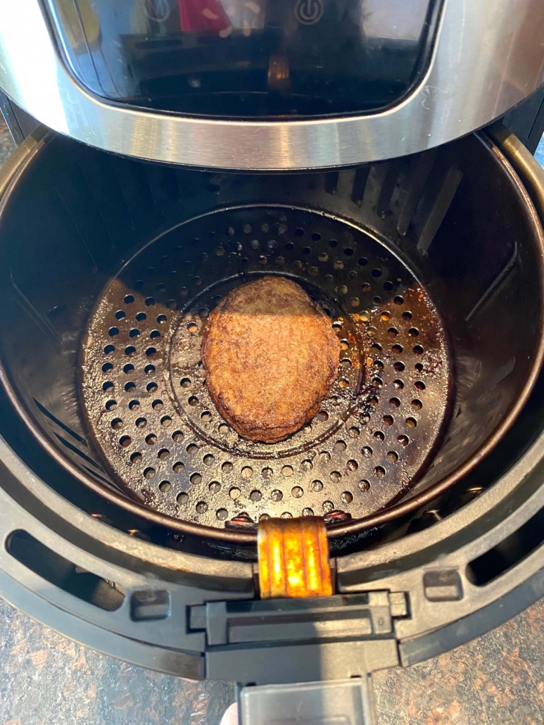 air fryer basket entering air fryer with a turkey burger