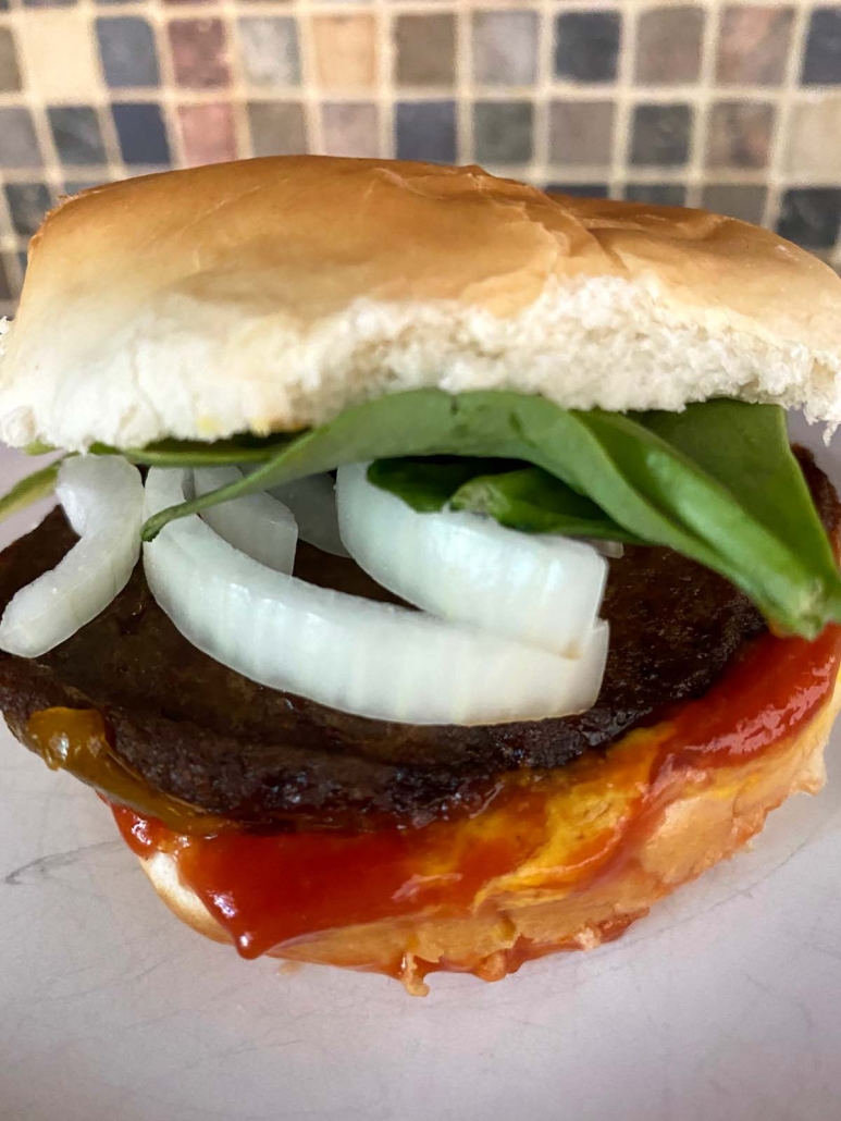 juicy turkey burger featuring bun, lettuce, onion, patty, and ketchup on plate