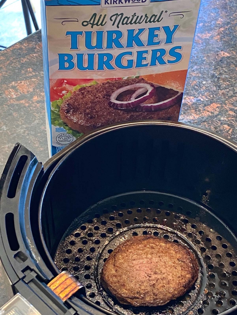 package of all natural frozen turkey burger next to air fryer basket with turkey burger inside