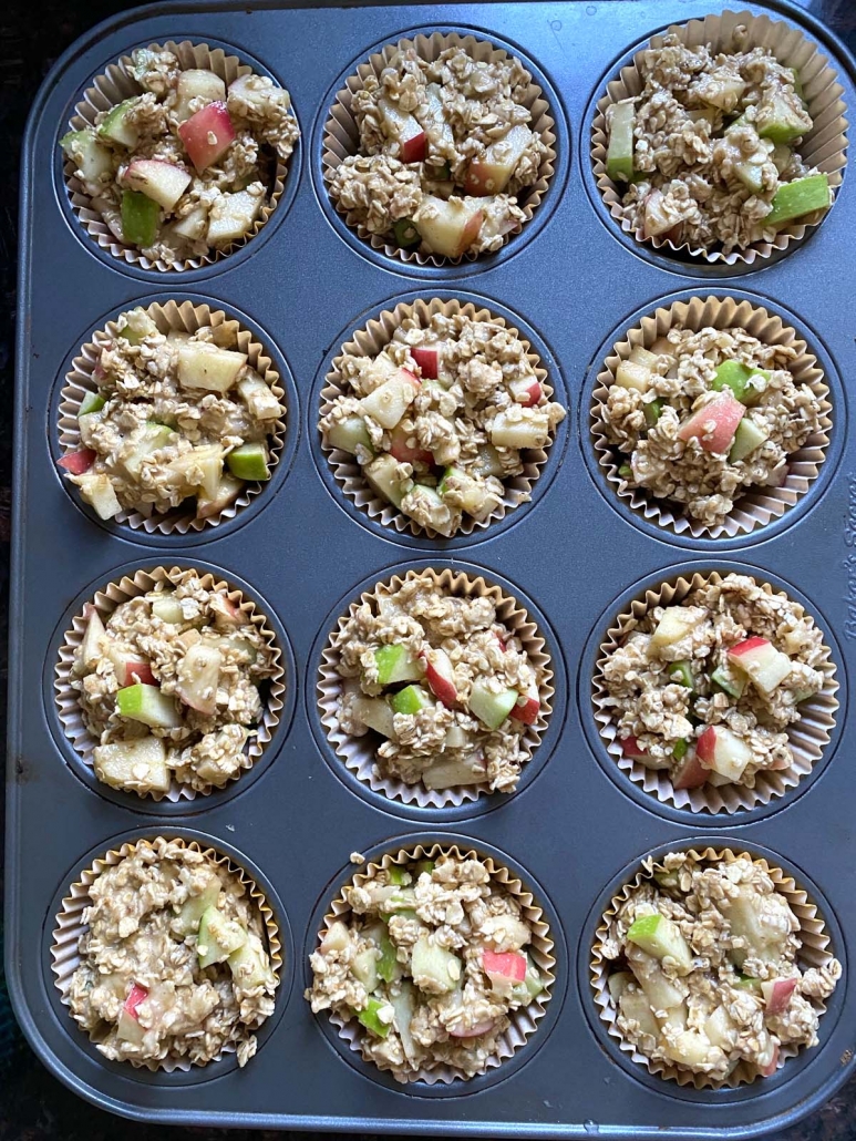 adding apple muffin mixture to muffin tin