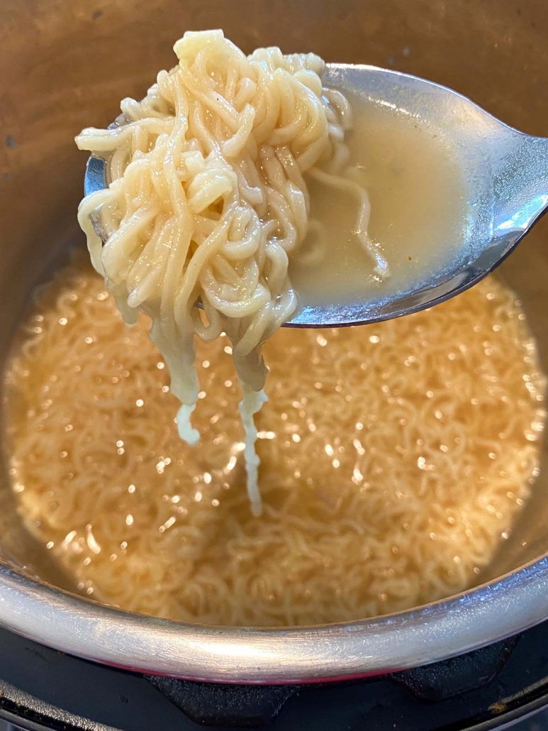spoon holding ramen noodles above instant pot