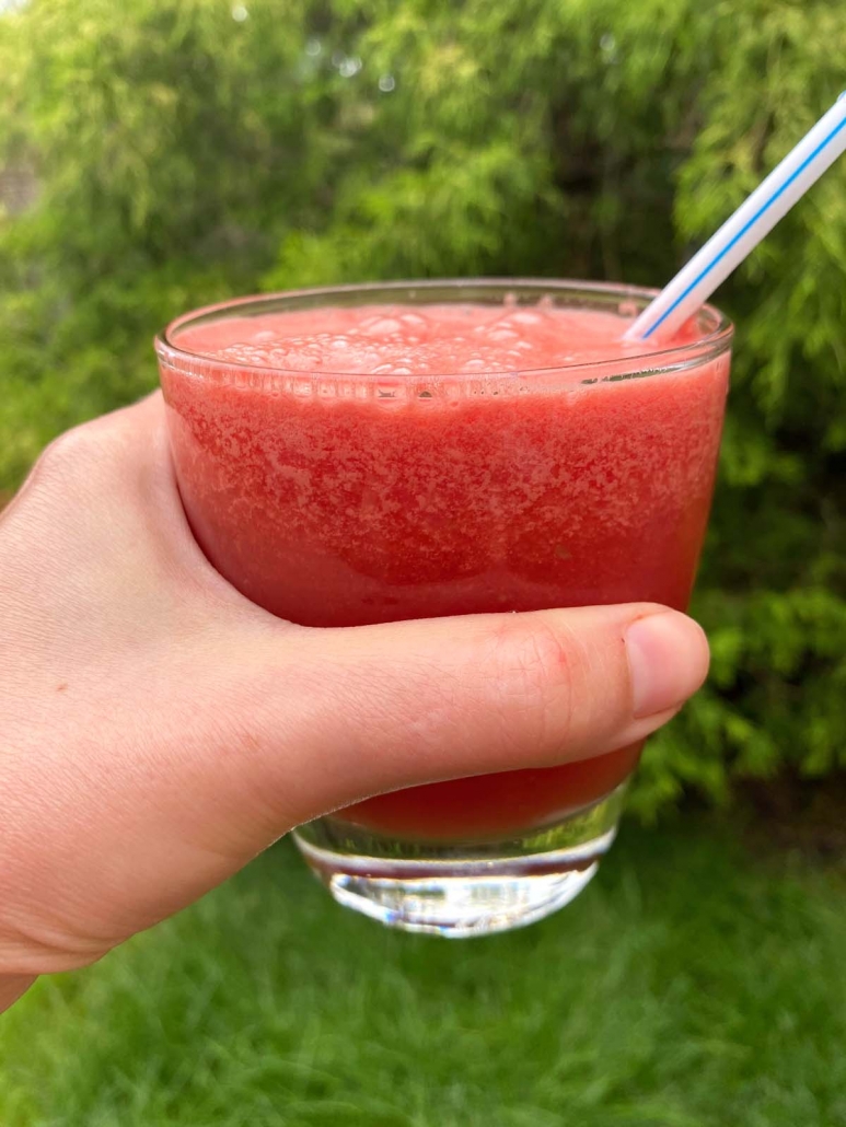hand holding glass of watermelon smoothie