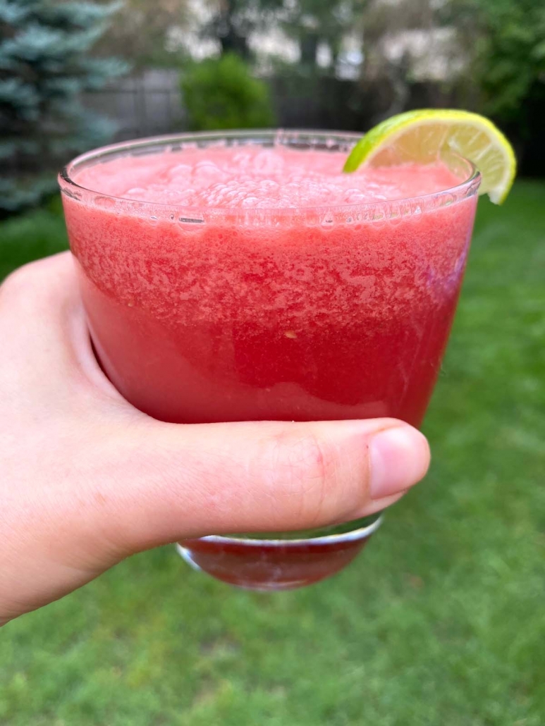 hand holding glass of watermelon drink outside