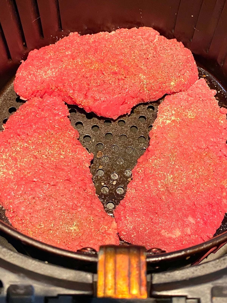close up of uncooked cube steak in air fryer
