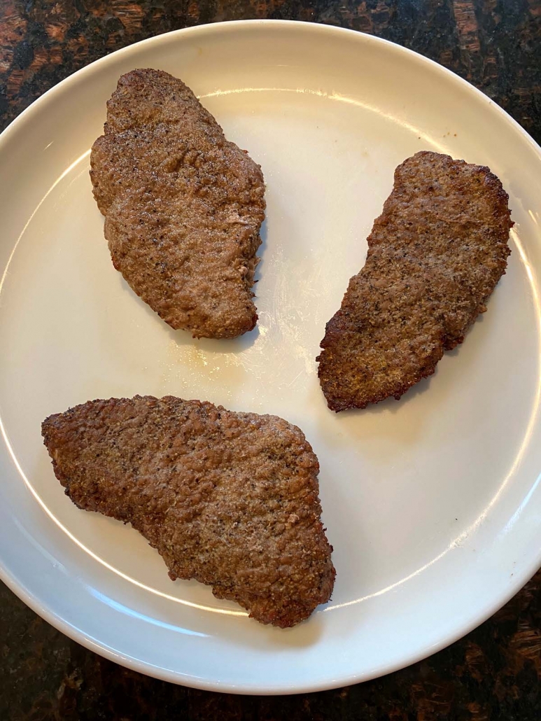 three pieces of cube steak on a white plate