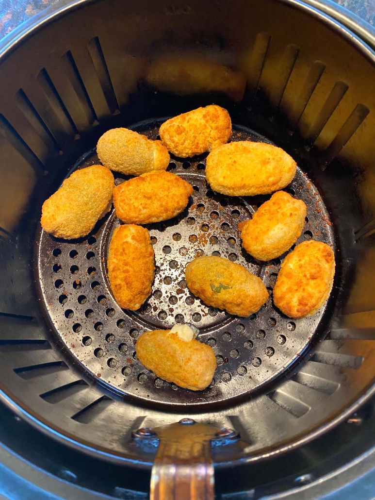 interior of air fryer basket with frozen jalapeno poppers