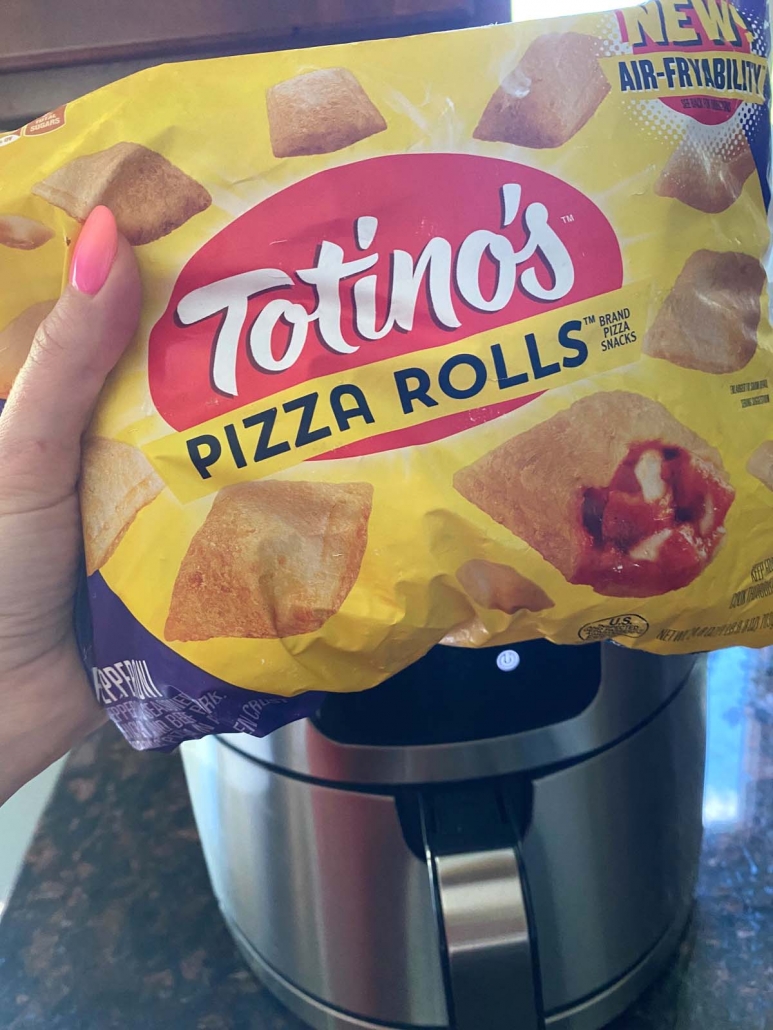 hand holding package of pizza rolls in front of air fryer