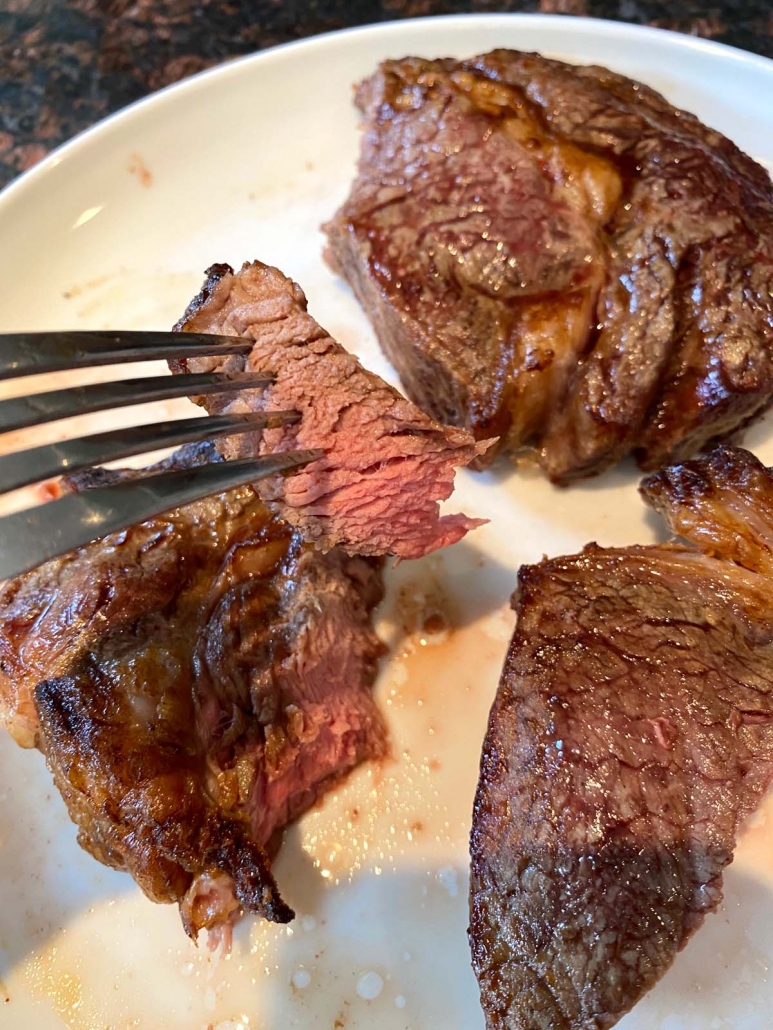 eating a piece of ribeye steak with a fork