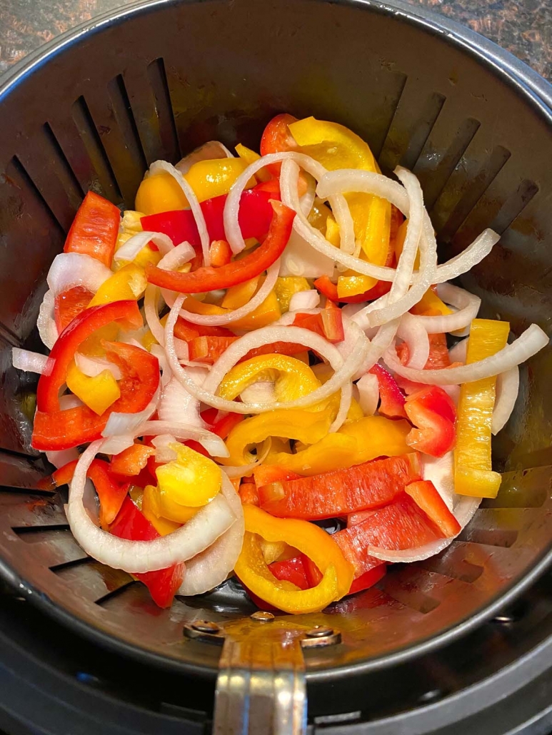 sliced peppers and onions in air fryer basket 