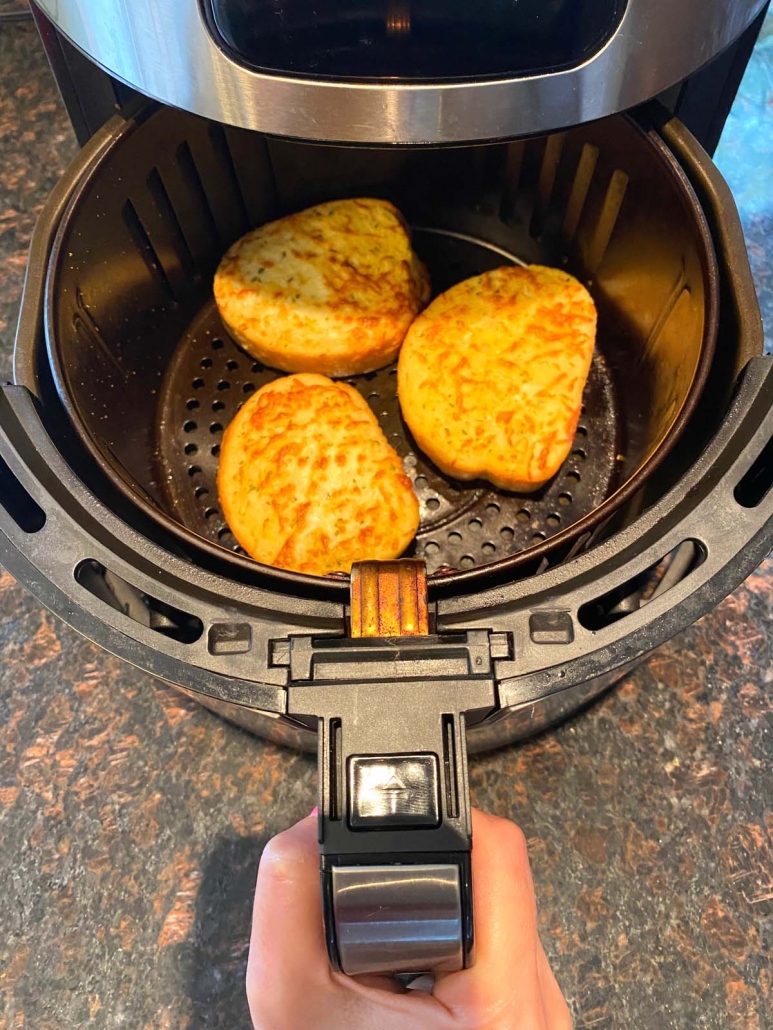 hand holding air fryer with texas toast inside