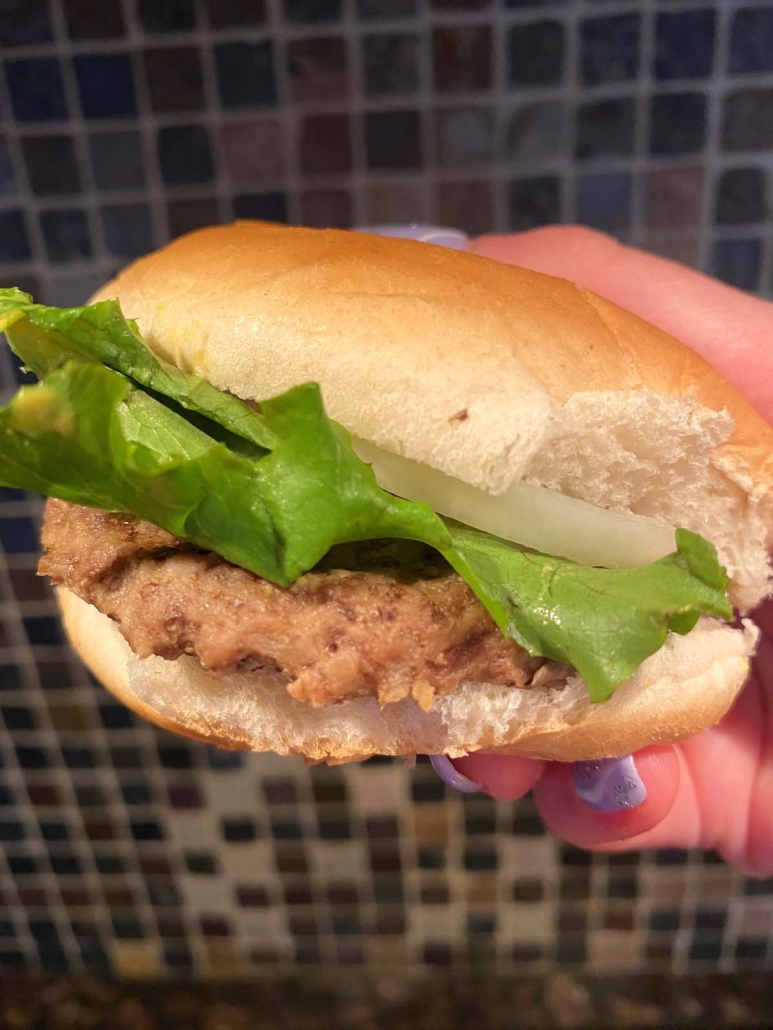 hand holding burger with bun and lettuce