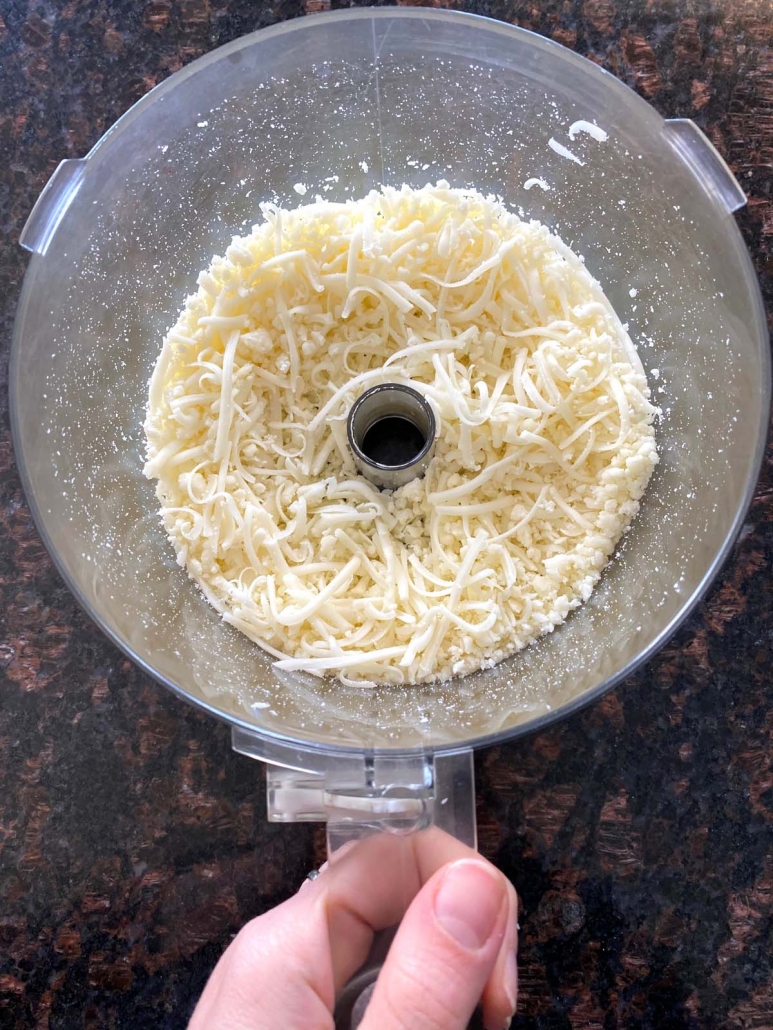 hand holding food processor with shredded cheese inside