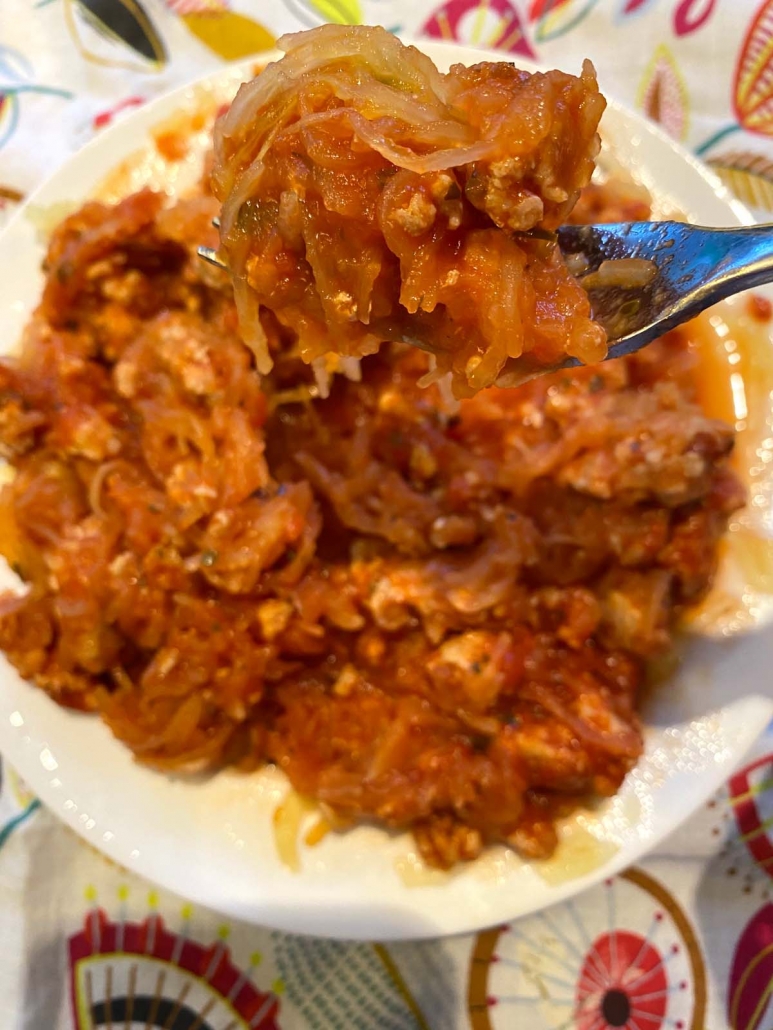 fork holding spaghetti squash with meat sauce over bowl