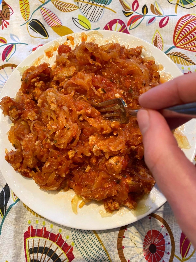 hand holding fork and stirring the meat sauce and spaghetti squash