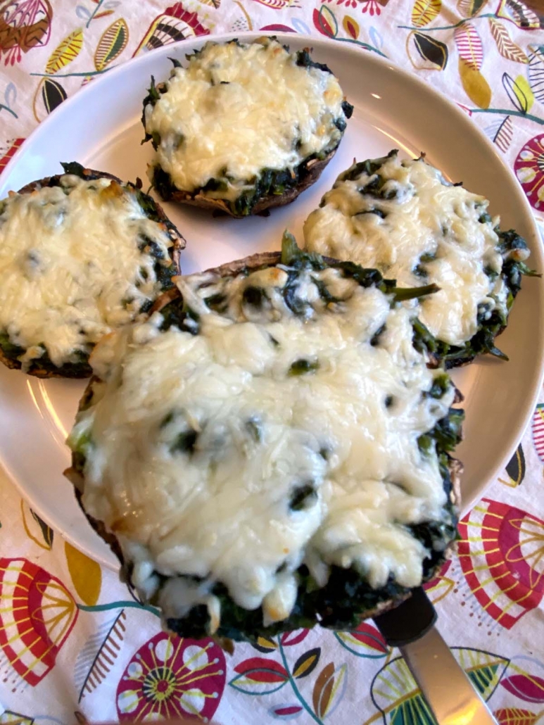 Serving spinach stuffed portobello mushroom with melted cheese from a plate.