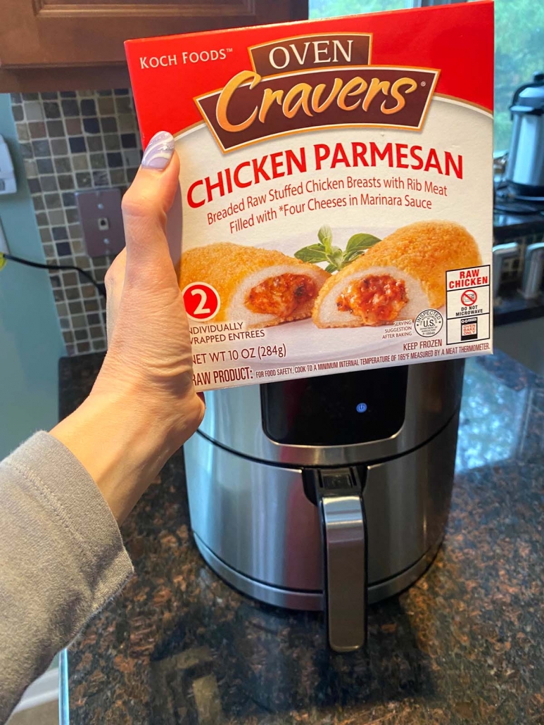 hand holding box of frozen chicken parmesan in front of air fryer